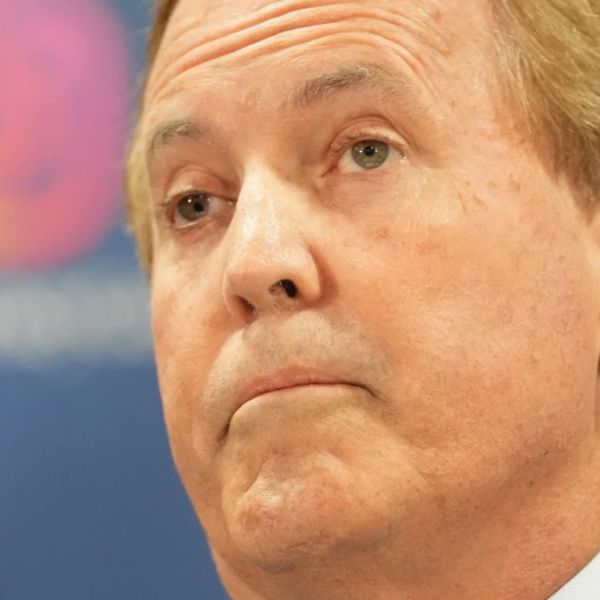 Close-up of a middle-aged man in a suit looking upward with a serious expression against a blue background.